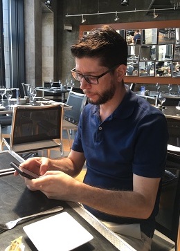 Philippe Papillon looking at his phone while waiting for a meal at a restaurant